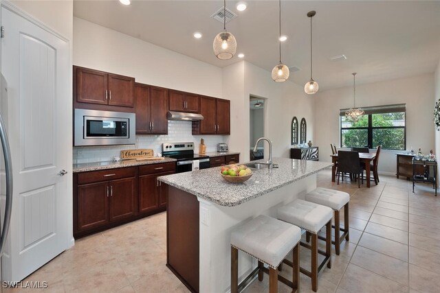 20956 Corkscrew Shores Blvd E, Estero, FL 33928 - kitchen featuring appliances with stainless steel finishes, a sink, light tile patterned flooring, backsplash, and a breakfast bar
