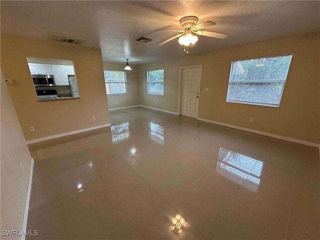 5550 Birdsong Ln, Bokeelia, FL 33922 - unfurnished living room with tile patterned floors, baseboards, and a ceiling fan