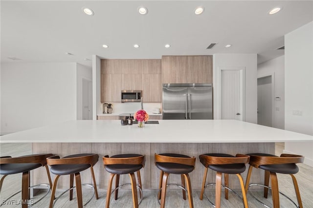 14931 David Dr, Fort Myers, FL 33908 - kitchen featuring appliances with stainless steel finishes, modern cabinets, recessed lighting, light countertops, and a breakfast bar area