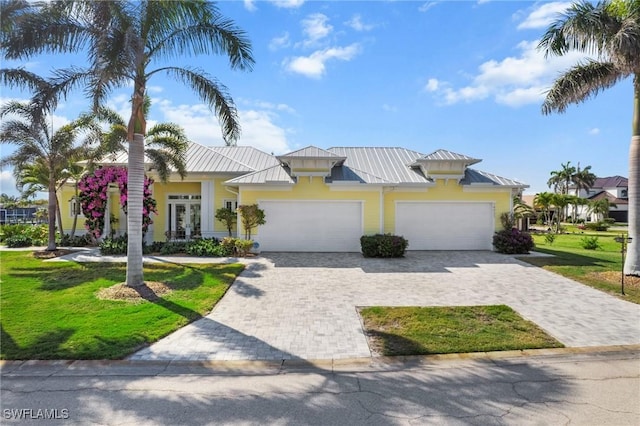 14931 David Dr, Fort Myers, FL 33908 - view of front of house featuring a standing seam roof, a garage, decorative driveway, a front lawn, and metal roof