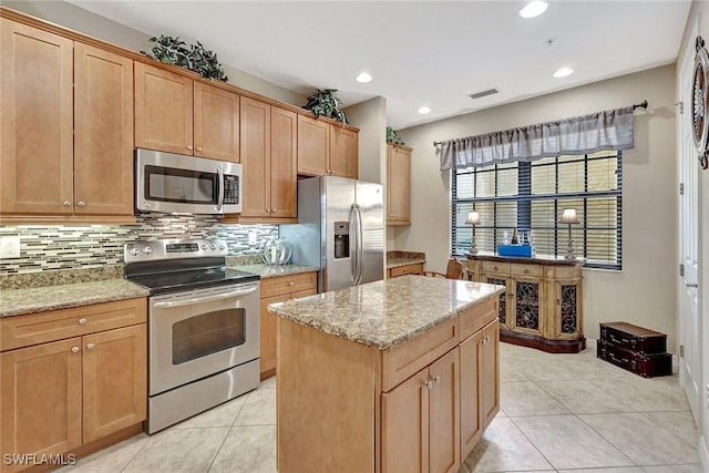 kitchen with appliances with stainless steel finishes, tasteful backsplash, a center island, light stone countertops, and light tile patterned floors