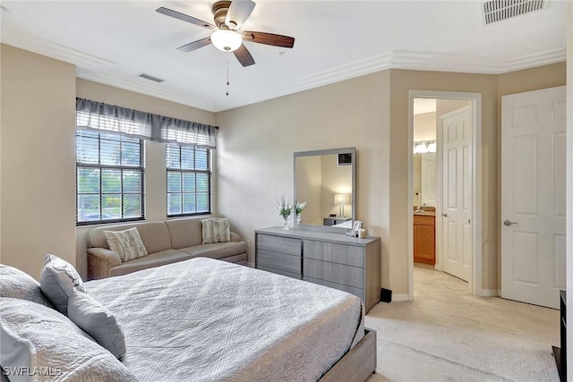 bedroom featuring light carpet, baseboards, ornamental molding, ensuite bathroom, and a ceiling fan