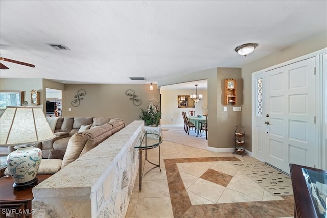 living room with light tile patterned floors, ceiling fan, a chandelier, and baseboards