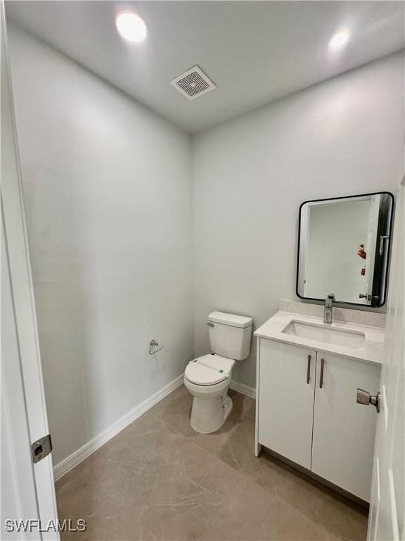 bathroom with toilet, baseboards, vanity, and recessed lighting