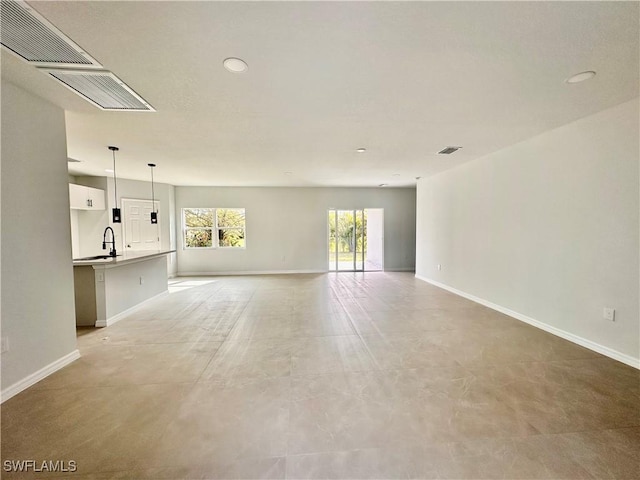 unfurnished living room with baseboards, recessed lighting, a sink, and concrete flooring
