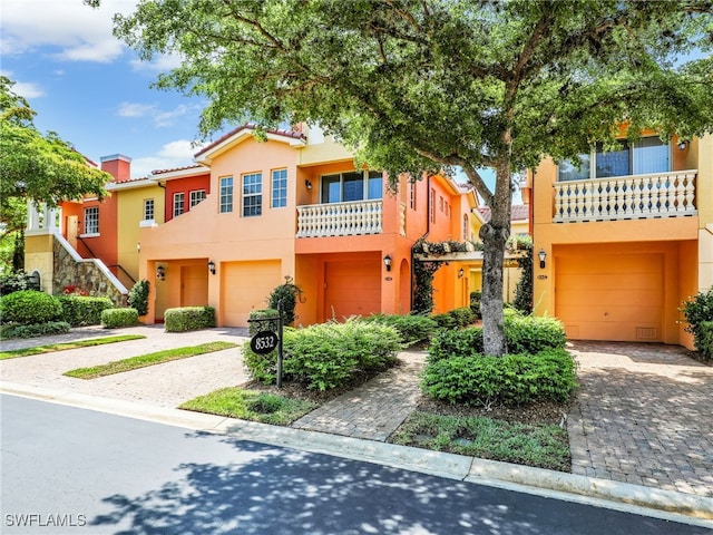 8532 Via Lungomare Cir Unit 203, Estero, FL 33928 - view of property with a garage, stucco siding, driveway, and stairs