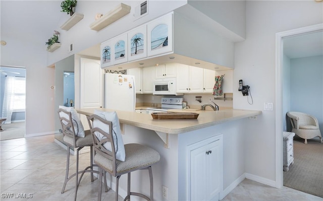 5825 Trailwinds Dr Unit 425, Fort Myers, FL 33907 - kitchen with white appliances, a kitchen bar, light countertops, a peninsula, and white cabinetry