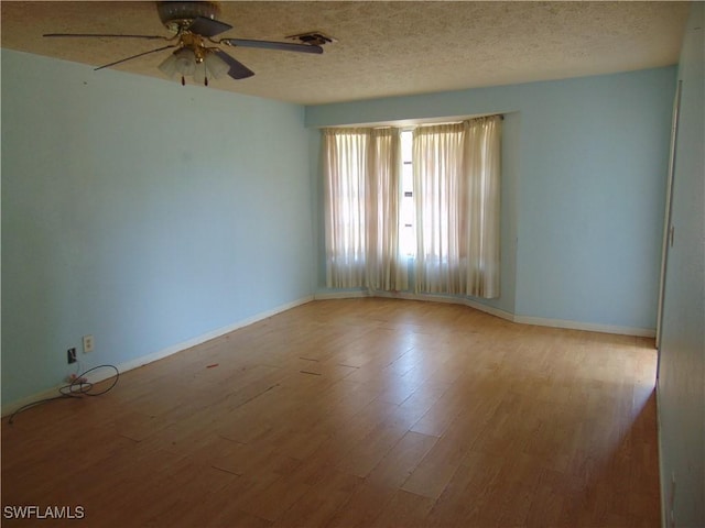 empty room featuring a ceiling fan, wood finished floors, baseboards, and a textured ceiling