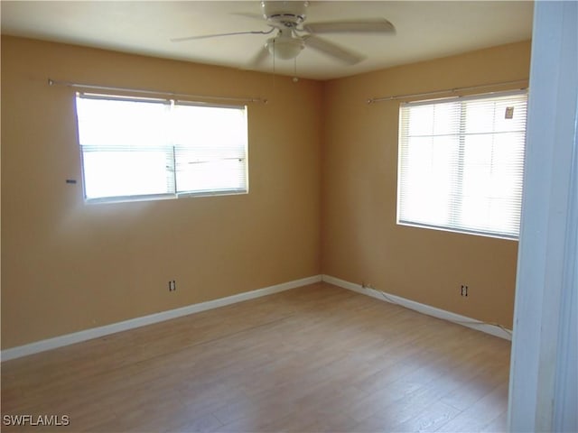 empty room featuring a ceiling fan, light wood-type flooring, and baseboards