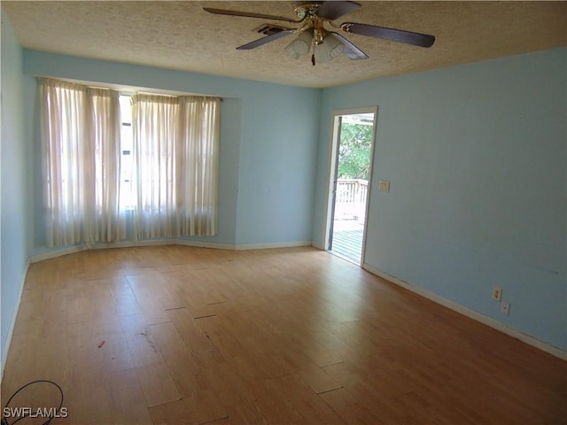 empty room featuring wood finished floors, a textured ceiling, a ceiling fan, and baseboards