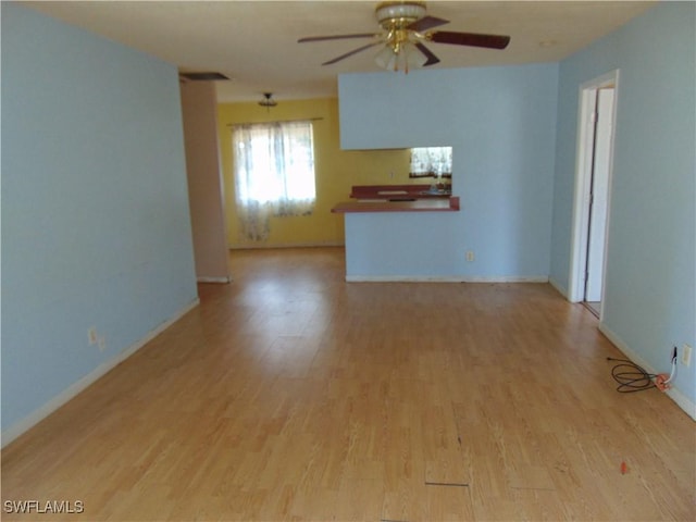 unfurnished living room featuring ceiling fan, light wood-style flooring, and baseboards