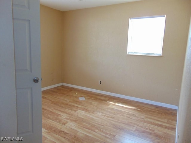 spare room featuring light wood-style floors and baseboards