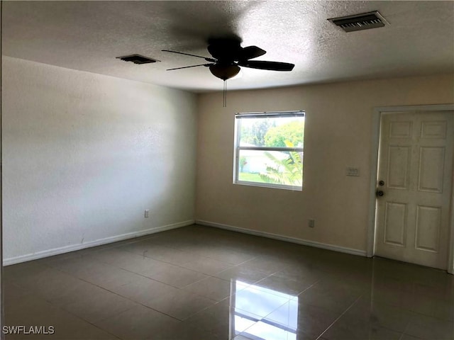 5615 Birdsong Ln, Bokeelia, FL 33922 - empty room featuring a ceiling fan, baseboards, tile patterned flooring, and a textured ceiling