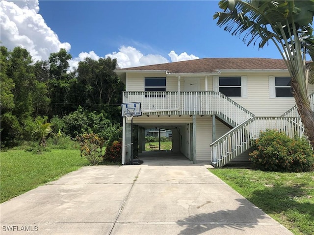 5615 Birdsong Ln, Bokeelia, FL 33922 - coastal home with a carport, concrete driveway, a porch, stairway, and a front yard