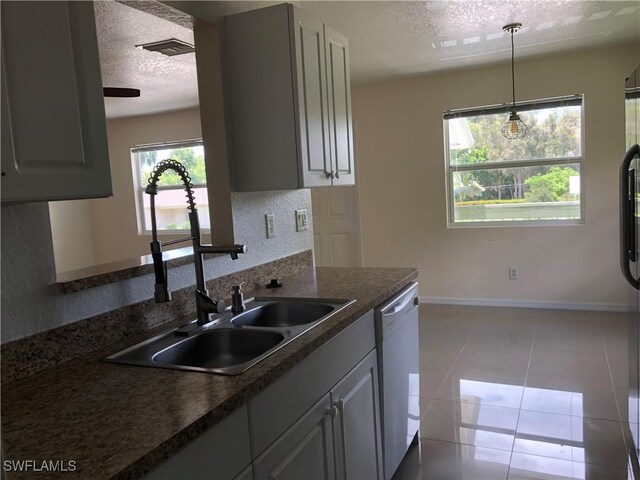 5615 Birdsong Ln, Bokeelia, FL 33922 - kitchen with dishwasher, a textured ceiling, a sink, dark countertops, and tile patterned flooring