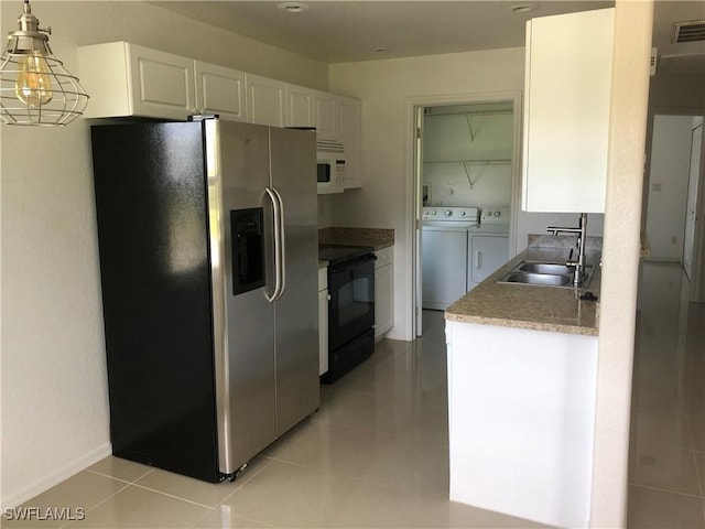 5615 Birdsong Ln, Bokeelia, FL 33922 - kitchen featuring stainless steel fridge, black range with electric cooktop, washer and dryer, a sink, and white microwave