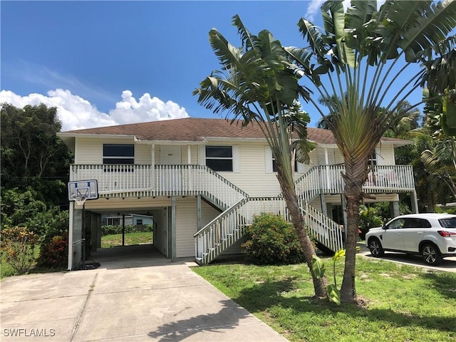 5615 Birdsong Ln, Bokeelia, FL 33922 - view of front of home featuring a carport, concrete driveway, a front yard, stairs, and a shingled roof