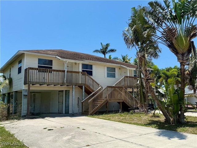 5615 Birdsong Ln, Bokeelia, FL 33922 - rear view of property featuring concrete driveway, a carport, stairway, and roof with shingles
