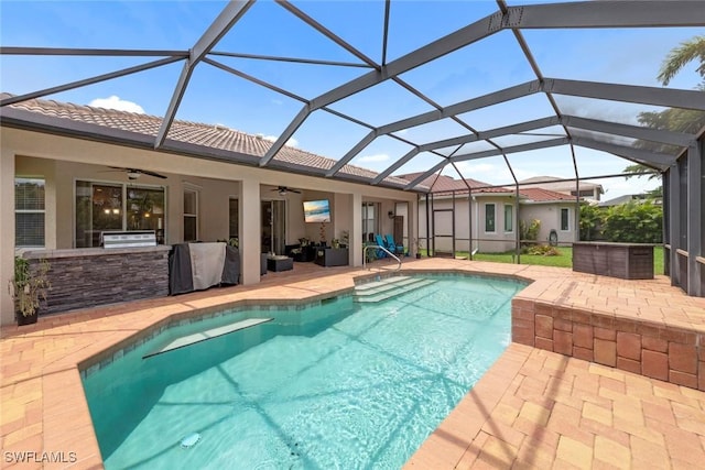 swimming pool featuring an outdoor kitchen, a ceiling fan, a patio area, and a lanai