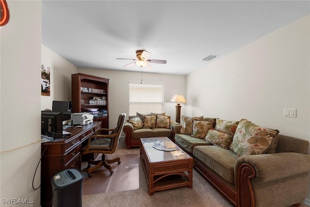 carpeted living room featuring a ceiling fan and a desk