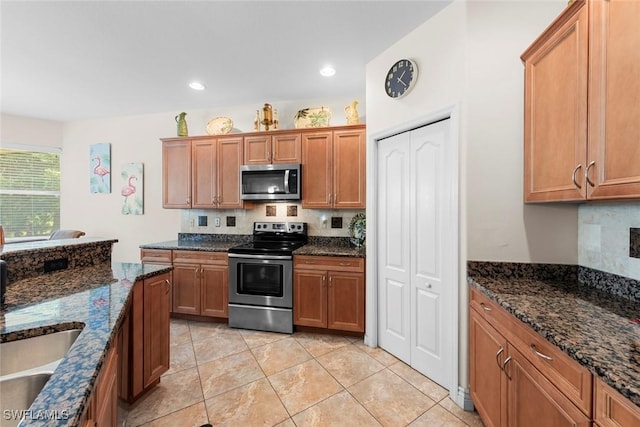 kitchen with appliances with stainless steel finishes, brown cabinetry, tasteful backsplash, dark stone counters, and recessed lighting