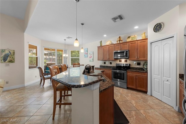 kitchen featuring stainless steel appliances, a sink, brown cabinets, a kitchen bar, and recessed lighting