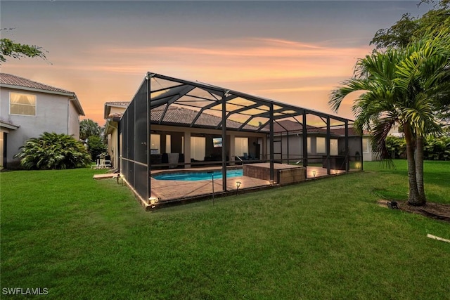 rear view of property featuring an outdoor pool, a yard, a patio area, and a lanai