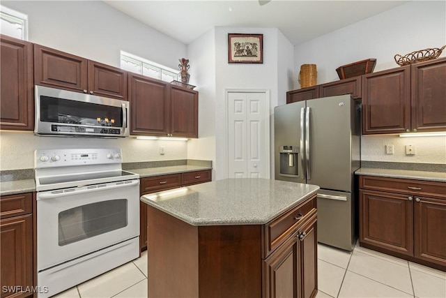 4081 Marianne Key Rd, Punta Gorda, FL 33955 - kitchen with stainless steel appliances, light tile patterned floors, a center island, and light stone countertops