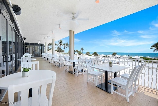 view of patio with outdoor dining space, a ceiling fan, and a water view