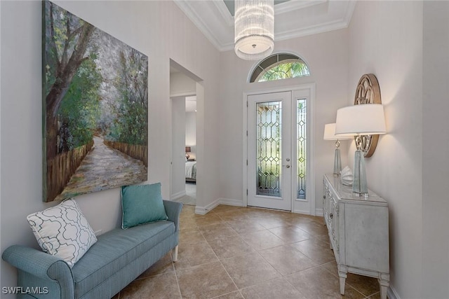 entryway with ornamental molding, a high ceiling, a chandelier, tile patterned floors, and baseboards