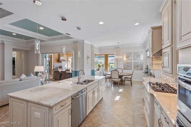 kitchen featuring a sink, stainless steel appliances, cream cabinets, crown molding, and open floor plan