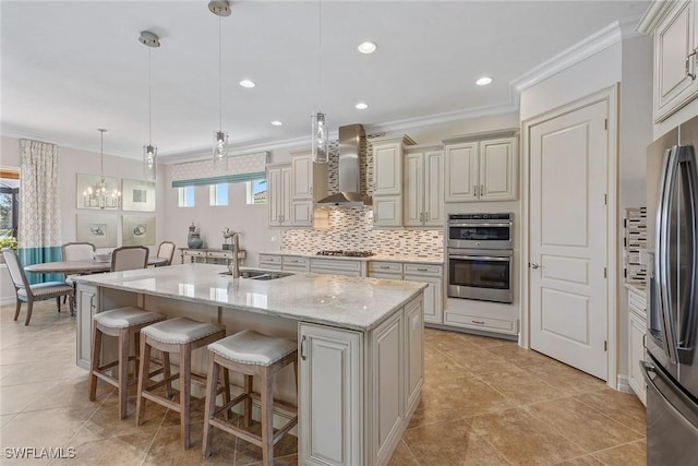kitchen with wall chimney exhaust hood, a sink, stainless steel appliances, a kitchen breakfast bar, and tasteful backsplash