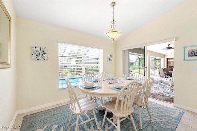 dining area featuring ceiling fan, baseboards, light tile patterned flooring, and vaulted ceiling
