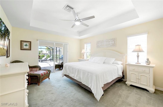 bedroom with a raised ceiling, access to exterior, and light carpet