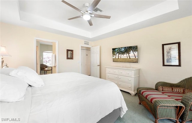 bedroom featuring a tray ceiling, carpet, and a ceiling fan