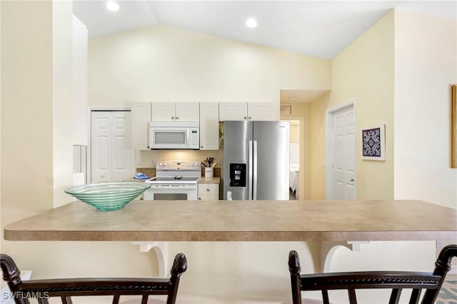 kitchen with white appliances, a breakfast bar area, light countertops, and high vaulted ceiling