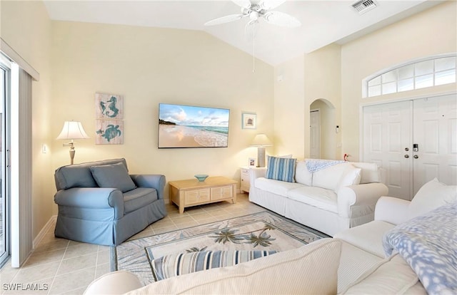 tiled living area with arched walkways, ceiling fan, high vaulted ceiling, and baseboards