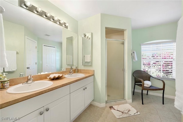 bathroom featuring a stall shower, double vanity, baseboards, and tile patterned floors