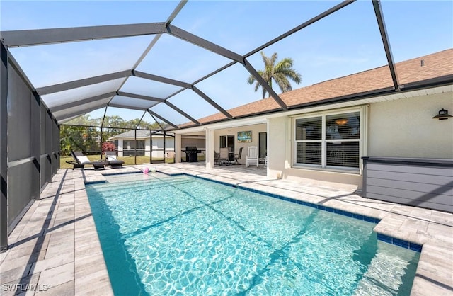 swimming pool with a patio area, glass enclosure, and a grill