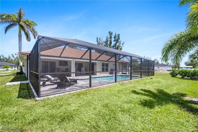rear view of property featuring a patio, a yard, an outdoor pool, and glass enclosure