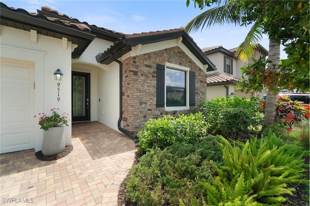 9519 Foxglove Ln, Naples, FL 34120 - doorway to property featuring stone siding, stucco siding, a tile roof, and an attached garage