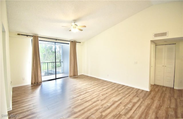 empty room with wood finished floors, a ceiling fan, expansive windows, lofted ceiling, and baseboards