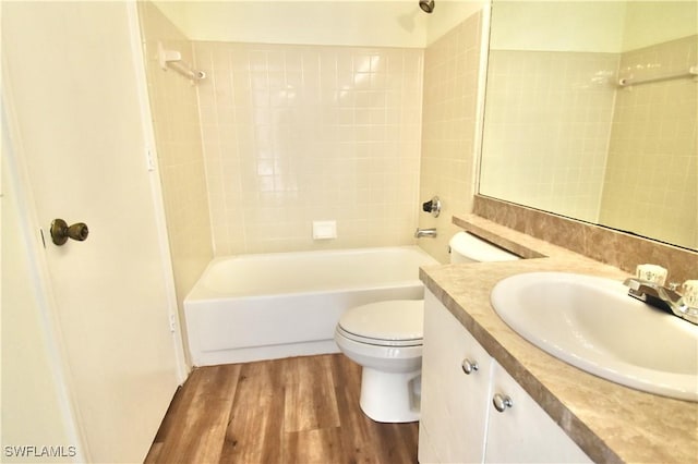 bathroom featuring toilet, wood finished floors, washtub / shower combination, and vanity