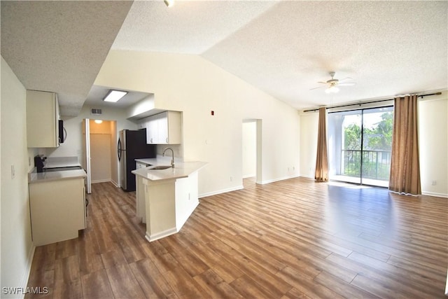 kitchen with open floor plan, freestanding refrigerator, dark wood-style flooring, a textured ceiling, and a sink