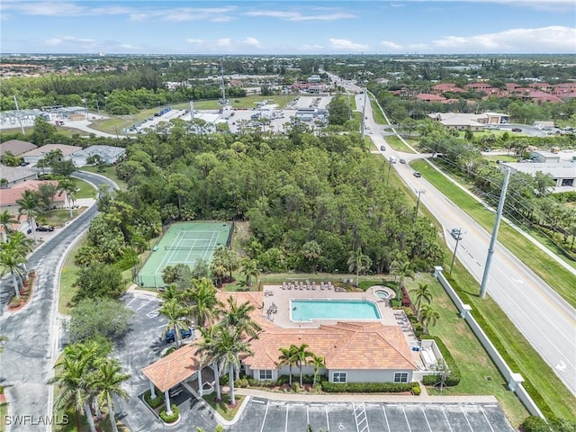 aerial view of property and surrounding area with a pool and a tree filled landscape