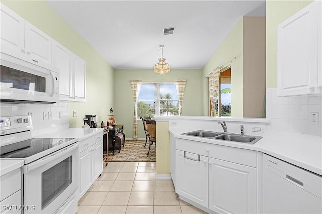 kitchen with white appliances, a sink, white cabinetry, decorative backsplash, and light countertops
