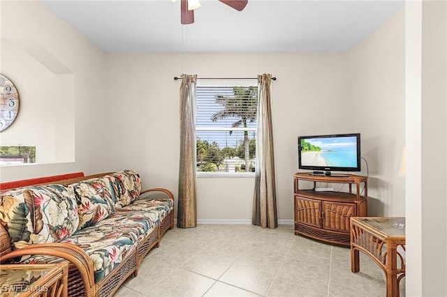 living area with healthy amount of natural light, a ceiling fan, light tile patterned floors, and baseboards