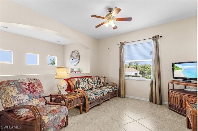 living room featuring a ceiling fan, baseboards, tile patterned flooring, and arched walkways