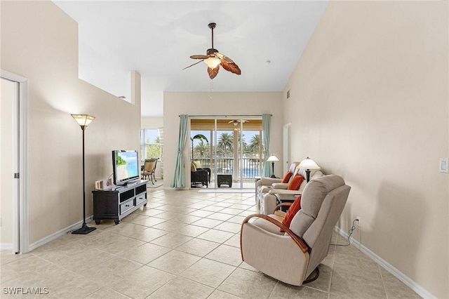 living area with ceiling fan, light tile patterned flooring, high vaulted ceiling, and baseboards