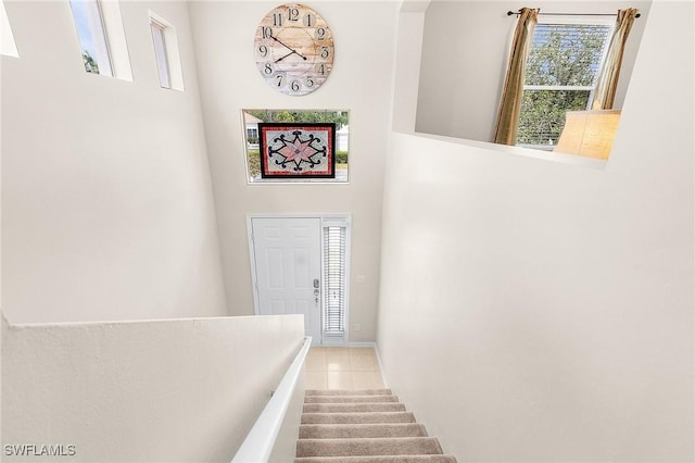stairway featuring tile patterned floors, a towering ceiling, and baseboards